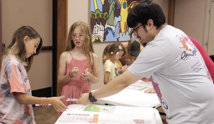 Shawnee Public Library Children's Librarian Jairo Montelongo gives change to Hadley Blake, 10, of Bethel, during the 'Pet Cents' event on June 14. Using play money, Blake bought an ostrich for her pet, and Brylynn Pointer, 11, of Shawnee, bought a giraffe. Montelongo said the library received an American Library Association grant to teach children how to manage finances. Their next event, Making Moo-La, will be on June 21 at 10:30 am.