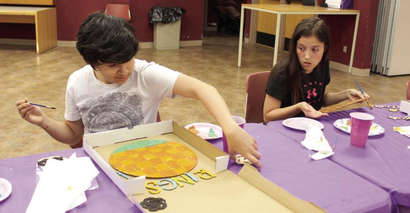 Siblings Mason and Melody Deanda, of Shawnee, work on painting door sign projects at the 'Paint Together' event at Shawnee Public Library on June 10.