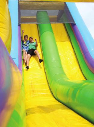 Eli Storie and Chaistyn Ramsey, both 10 and of Tecumseh, slide together down the inflatable slide during the Mingle on Main Street Block Party on June 16. Countywide &amp; Sun/Natasha Dunagan
