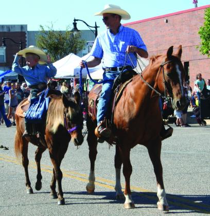 A little cowboy tips his hat as an older cowboy leads his horse in the Frontier Days Parade on Sept. 30. Countywide &amp; Sun/Natasha Dunagan