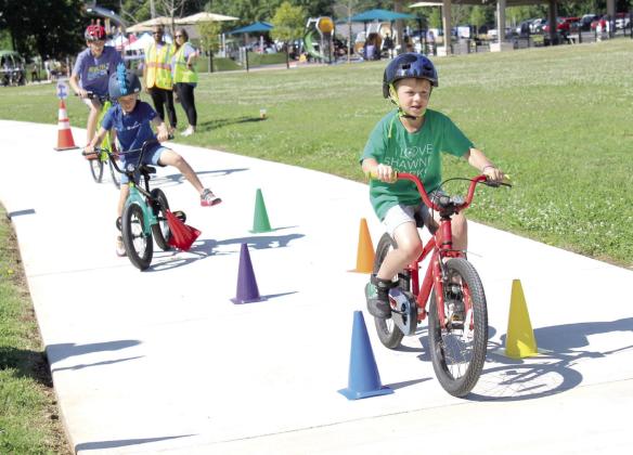 Dillon Beck, 7, of Shawnee, leads two other bicyclists during the Bike Safety Blitz at the Fun Day at Kidspace Park in Shawnee on May 30. Fun Day was part of Health Week, which is sponsored by the Avedis Foundation, and offered a variety of activities in the morning and evening. Pottawatomie Go (POGO) sponsored the bike safety event and several other events. Natasha Dunagan, Countywide &amp;amp; Sun