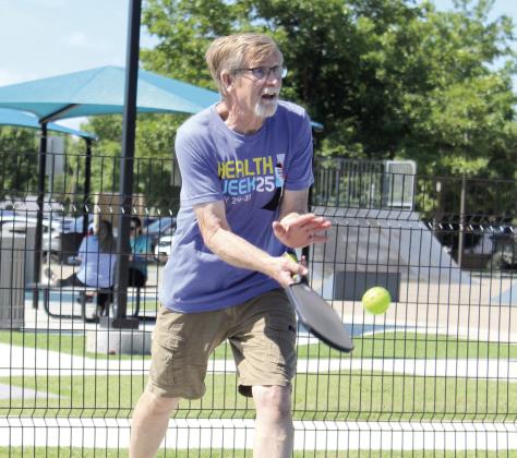 Craig Noble, a volunteer from Shawnee Parks and Recreation, teaches three children how to play pickleball during the Fun Day at Kidspace Park. Natasha Dunagan, Countywide &amp;amp; Sun