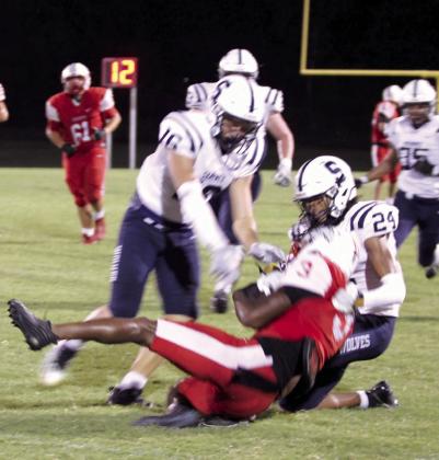 Shawnee junior Jayden Smith (16) and senior Dace Shaw (24) tackle McLoud junior Zaylun Matlock and try to take the ball during the scrimmage.