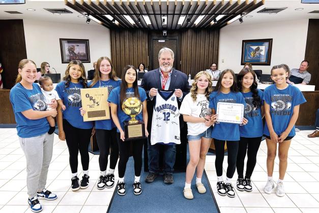 On behalf of the Shawnee Board of City Commissioners, Mayor Eric Stephens presented a Certificate of Recognition to the Pleasant Grove Girls Basketball team who won their second consecutive ORES Division III Championship. The Lady Warriors then presented Stephens with a signed jersey. Shawnee High School Girls Swim Team was also recognized for securing their fourth consecutive OSSAA 5A State Championship title. Both teams received a challenge coin from the Mayor. Photo provided by City of Shawnee