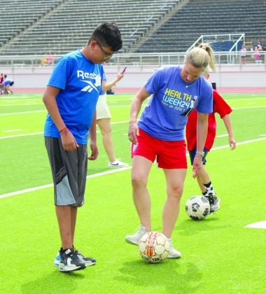 Lindsay Tarpley gives Aron Garcia pointers on how to control the ball at her soccer demonstration, sponsored by POGO for Health Week, at Jim Thorpe Stadium, May 28. Countywide &amp; Sun/Natasha Dunagan