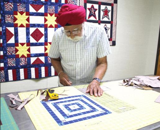 Bhupinder S. Obrai trims pieces for a quilt backing during the Spinning Spools Quilt Guild Quilt Camp on June 25. He completed a Cars-themed baby quilt top at camp the day before.