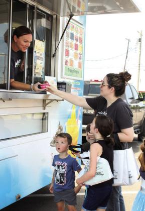 Peachwave Yogurt co-owner Kim Smith serves Stephanie Oldham, of Shawnee, and her children Shepherd, 3; Bear, 6; and Tensie, 8, after the Tecumseh Public Library "Mobile Dairy Classroom" program on June 26. About 100 attendees enjoyed free frozen dairy treats paid for by Tecumseh Friends of the Library and Tinker Federal Credit Union. The Tecumseh library will present "Sound of Music Interactive" by Lyric Theater of Oklahoma on July 10 at 2 pm. Natasha Dunagan, Countywide &amp; Sun