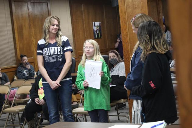 Horace Mann student Scottlyn Miller speaks about her drawings as her art teacher Angie Sack, principal Jennifer Epperly, and Raighen Hendrix look on at the Shawnee Board of Education meeting Jan. 10.