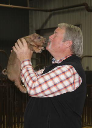 Randy Gilbert kisses Stitch the Duroc piglet for United Way.