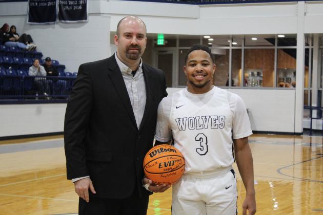Coach Eric Litherland presents the 1000-point game ball to Jaylon Orange. Orange reached 1000 points in the Feb. 11 game against Guthrie.
