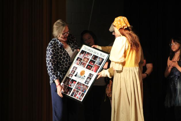 Tecumseh seniors Lillian Effinger and Jadon Jackson present a collage with pictures by Baylee Sutton to Vocal Music Director Cheryl Blankenship.