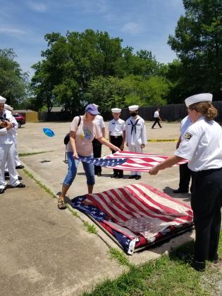 Cheryl Cowden, of Shawnee, brings a flag which belonged to her father to be retired, laying it on the pile to be burned, with the assistance of Diana Murray, of the U.S. Naval Sea Cadets Training Ship Oklahoma. Regional Sea Cadets Director Donna Snodgrass said about 25 flags were retired at the American Legion Hill-Huett Post 260, in Tecumseh, on June 11.