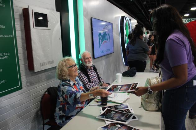 Sue Nelson sells a program, as Dr. Joe Taron looks on. Nelson has been the Faith 7 Bowl Treasurer for 25 years.