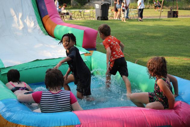 Neighborhood children enjoy the inflatable water slide.