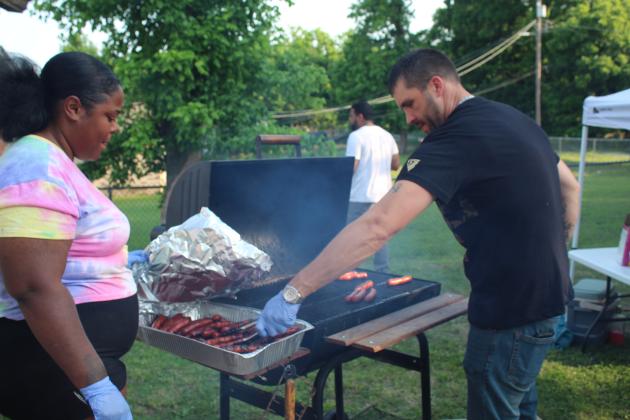 Tyler Land grills hot dogs, as Shawndrick Washington helps.