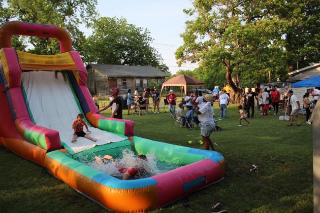 Neighborhood children enjoy the inflatable water slide.
