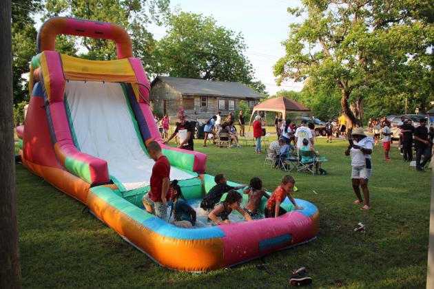 Neighborhood children enjoy the inflatable water slide.