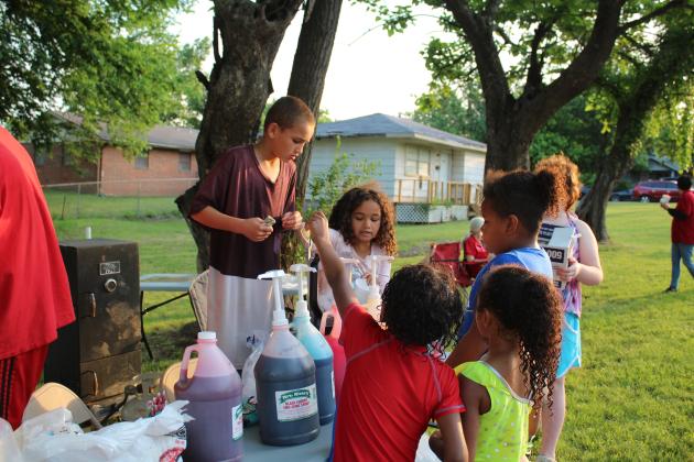 Kash Tillis, 9, and Makayla Tillis, 10, serve snowcones to children during "The Block is Hot: Live Music Block Party" on May 28 in the Dunbar Heights neighborhood of Shawnee. They are the grandchildren of Remetia Tillis who owns "Two Chicks Cookin'" food truck.