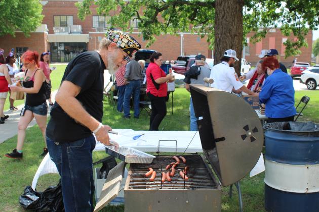 American Legion Post 16 Post Services Officer Jim Vaughn takes hotdogs off the grill as other American Legion and VFW volunteers serve them, following the Memorial Day Ceremony at the Oklahoma Veterans Memorial Park (Woodland Veterans Park) on May 30. Vaughn said he was part of the last airborne unit to leave Berlin in 1976.