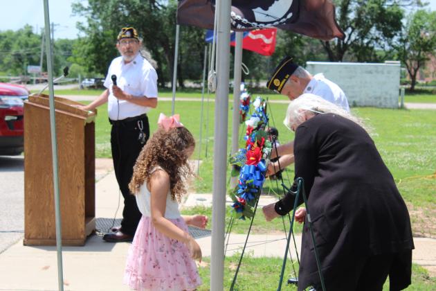 Sarah Jett watches as Stuart and Carolyn Rose secure a wreath against the wind.