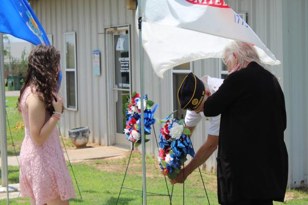 Esther Jett &amp; Carolyn Rose watch as Stuart Rose secures a wreath.