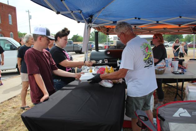 Danny and Shelby Mellinger, of Tecumseh, sell barbecue sandwiches to Donavan and Destiny Parker.