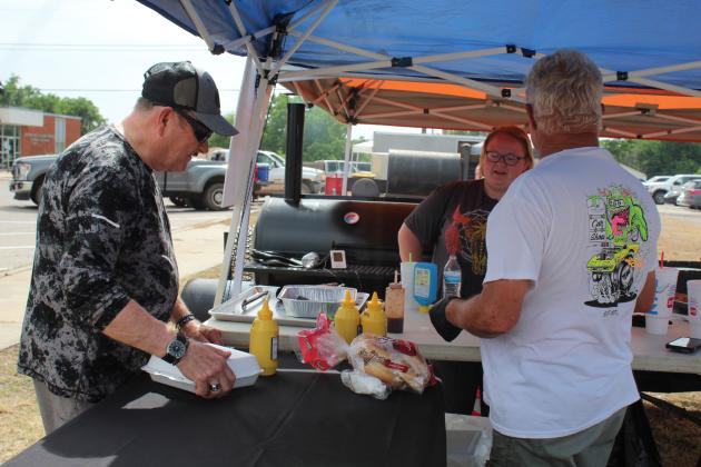 Danny and Shelby Mellinger, of Tecumseh, sell a barbecue sandwich to Charles Handy.