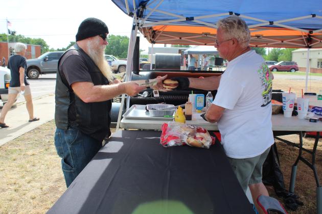 Danny Mellinger, of Tecumseh, right, sells a barbecue sandwich to Brian Cartwright, also of Tecumseh, during the Mingle on Main Street Block Party on June 16. Mellinger took first-place in the chicken breast division of the barbecue contest. Countywide &amp; Sun/Natasha Dunagan