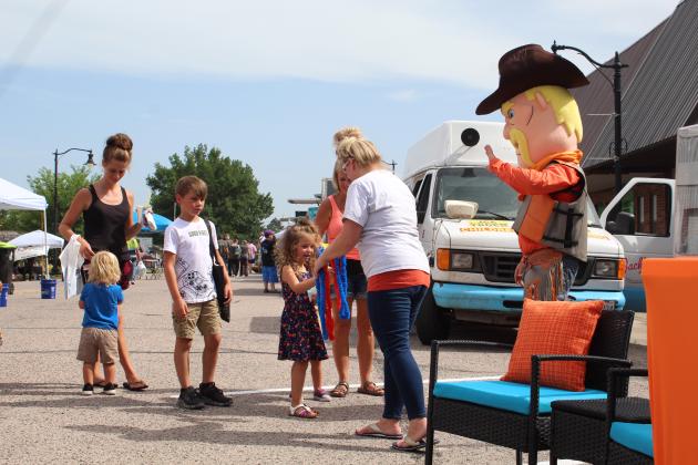 Cowboy Hank and Cally Powell, of Cowboys Plumbing, hand out plastic leis to children at Mingle on Main, June 16.