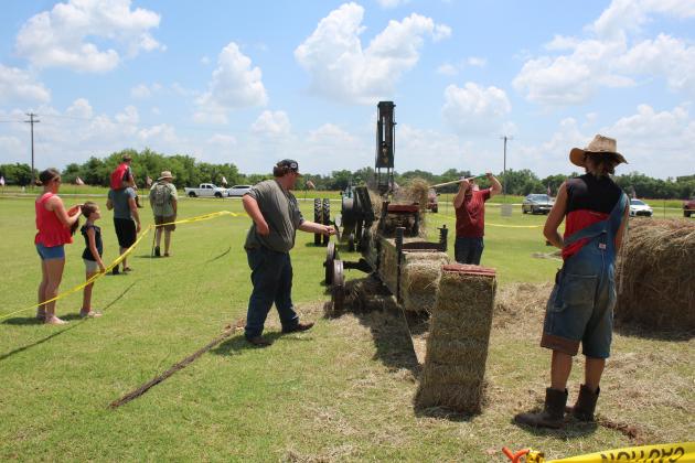 Jacob Vincent, of Shawnee, center, feeds wire into a 1920s baler, as Luke Bradley, of Prague, puts hay in the hopper, and Josh Peterson, of McLoud, prepares to move a square bale produced by the machine. Demonstrations such as this could be seen at the 23rd Annual Farming Heritage Festival,  held at Shawnee Feed Center on June 17-18. Countywide &amp; Sun/Natasha Dunagan