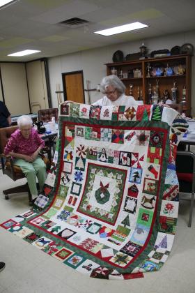 Charter member Ann Cosgrove shows the quilt top she completed, which was made from quilt squares she has received at guild Christmas parties over the years.