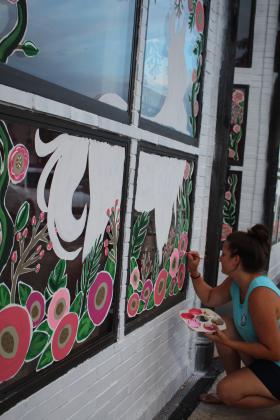 Lizzy Brady paints the Beauty Barn's windows.