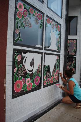 Lizzy Brady paints the Beauty Barn's windows.