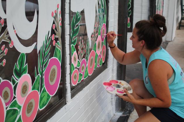 Lizzy Brady paints the Beauty Barn's windows.