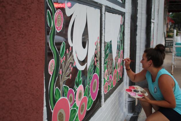 Lizzy Brady paints the Beauty Barn's windows.