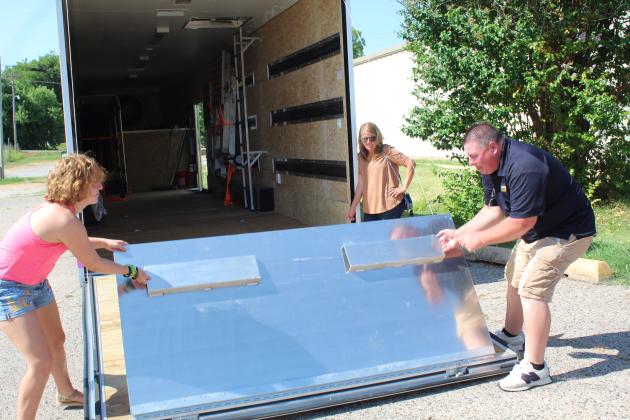 Tecumseh band student Laycee Thoma helps band director John Outon to lower the ramp on the new band trailer, as Thoma's mother, Anita Thoma, looks on.