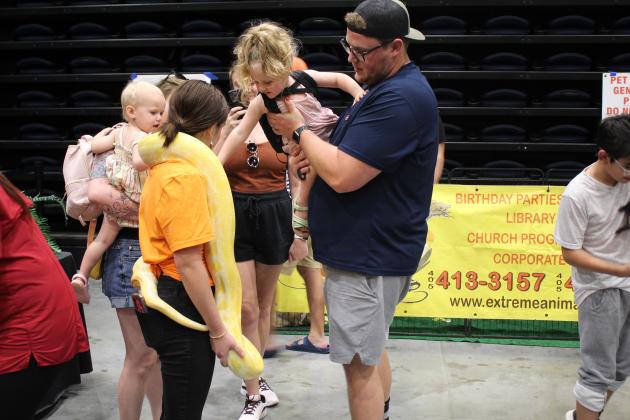 Emma Wells holds an albino python as children reach to pet it.