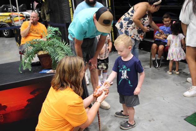 Volunteer Laura Wells holds a corn snake for a boy to pet.