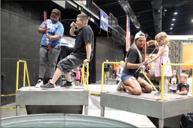 Jadelyn Greer, 15, of Shawnee, and Quinn Jones, 3, of Yukon, get help target bowfishing from Zak McMunn and Jaci Statton, respectively, from Darkwater Adventures of Meeker during the Outdoor Nation Expo on Aug. 13. Countywide &amp; Sun/Natasha Dunagan