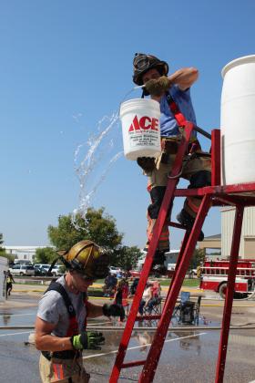 A Shawnee firefighter gets doused after handing his bucket to teammate Lane Williams during the Bucket Brigade of the Firefighter Olympics on Sept. 10. Teams from Asher, McLoud, Tecumseh, and Prague also participated. Countywide &amp; Sun/Natasha Dunagan