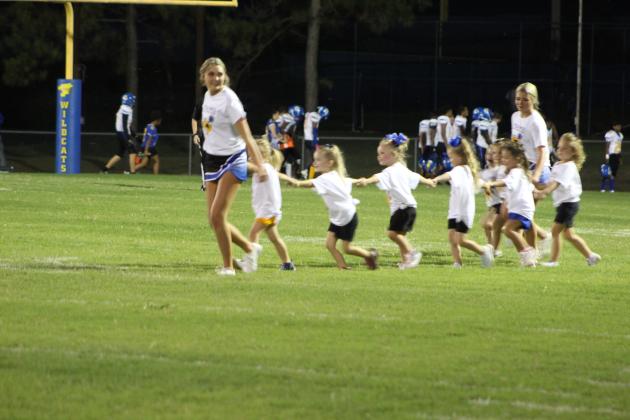 The Little Miss Wild Kitty cheerleaders are led onto the field by Bethel High School cheerleaders.