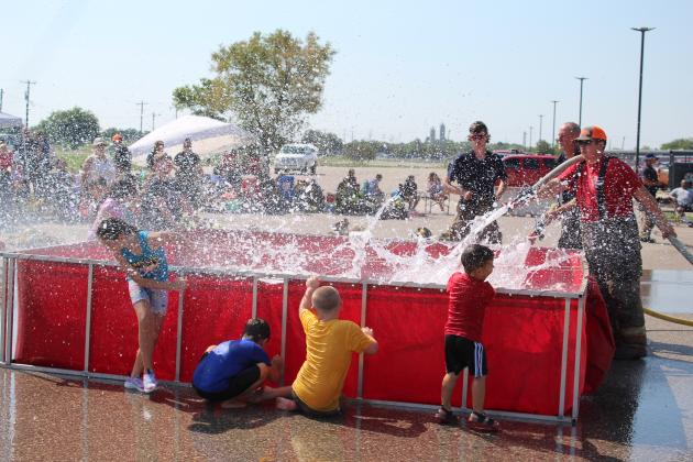 Bud Crawford, of Konawa, far right, and Steve Reese, of Asher, fill a tank and provide some water fun for kids attending the Firefighter Olympics at the Pottawatomie County Free Fair on Sept. 10. The kids were also allowed to swim in the tank before it was used for the Bucket Brigade contest. Crawford was on the Asher team. Prague, McLoud, Tecumseh and Shawnee also participated. Countywide &amp; Sun/Natasha Dunagan