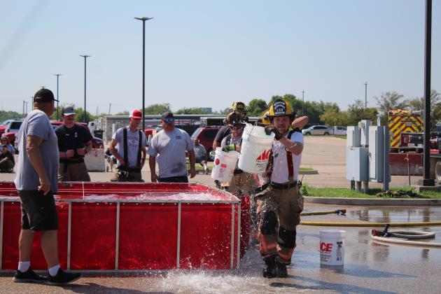 The Shawnee firefighter team starts their Bucket Brigade race  as Paul Simpson, far left, watches during the Firefighter Olympics at the Pottawatomie County Free Fair on Sept. 10. Simpson is a retired Shawnee firefighter and has coordinated the event since 1996. Teams from Asher, McLoud, Prague, and Tecumseh also participated. Countywide &amp; Sun/Natasha Dunagan