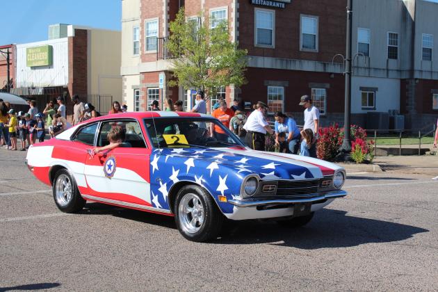 Donna Snodgrass, with the American Legion and U.S. Naval Sea Cadets, drives her 1971 Mercury Comet, as her grandson, Daryl Murray, hands out small flags during the Frontier Days Parade on Sept. 17. Countywide &amp; Sun/Natasha Dunagan