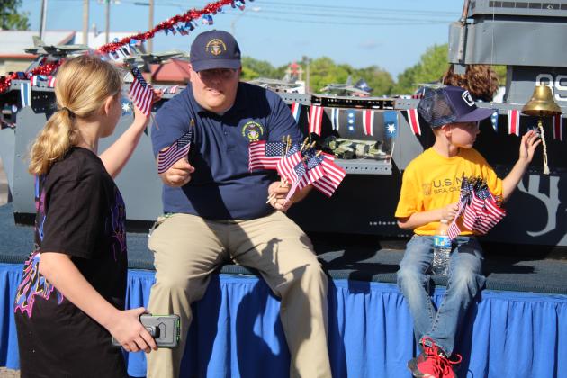 Members of the U.S. Naval Sea Cadets pass out small flags while riding on a float with the USS Sooner CV89 carrier vessel during Tecumseh's Frontier Days Parade on Sept. 17. Countywide &amp; Sun/Natasha Dunagan