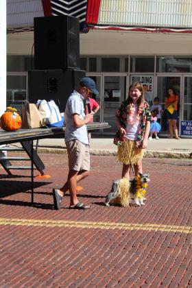 Ella Buss laughs at M.C. Waylon Sewell's jokes as she shows her dog, Silas, in his hula costume during the Monsters on Main pet contest, in downtown Shawnee, Oct. 22. Silas won third overall in the contest. Countywide &amp; Sun/Natasha Dunagan