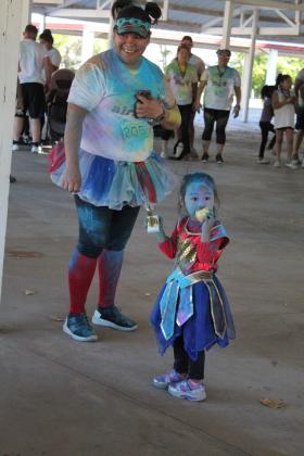Kathryn Risinger, 3, of Shawnee, eats an apple after receiving the "Best Costume" trophy during the House of Hope Color Fun Run on Oct. 1. Her mother, Samantha Nenaikita, smiles, as a fellow participant. Countywide &amp; Sun/Natasha Dunagan