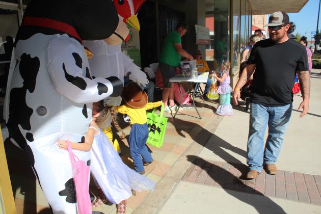Two trick-or-treaters give hugs to Lauren Garcia (the cow) and Brynyn Brown (the chicken), as Tyler Beam, of CREOKS hands out candy at Monsters on Main in downtown Shawnee on Oct. 22. CREOKS provides medical and mental health services in the area. Countywide &amp; Sun/Natasha Dunagan