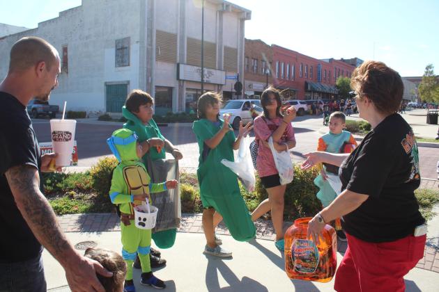 Pioneer Library Regional Coordinator Peggy Cook tosses bags of pretzels to trick-or-treaters at Monsters on Main in downtown Shawnee on Oct. 22. Countywide &amp; Sun/Natasha Dunagan