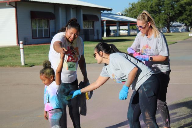 Whitney Coots and Deanna Voeks add some color to a young participant in the House of Hope Color Fun Run on Oct. 1 at the CPN Festival Grounds. The event was held in part to bring awareness to domestic violence, and signs with facts were posted along the route. Countywide &amp; Sun/Natasha Dunagan